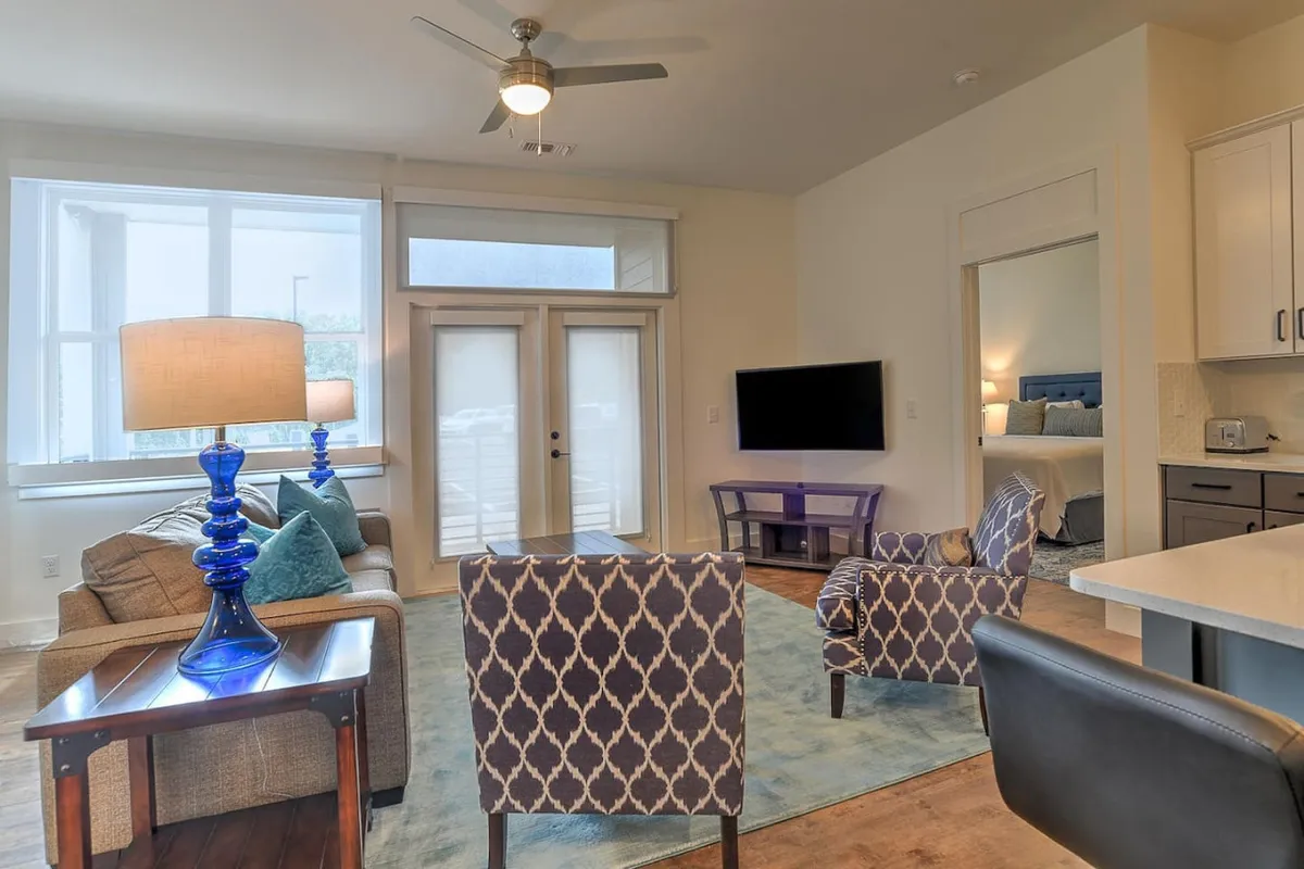 A cozy, contemporary space featuring a sofa, blue lamp, accent chairs, and a dining table. The arrangement emphasizes the seamless flow between the living and dining areas, enhanced by warm lighting and modern decor.