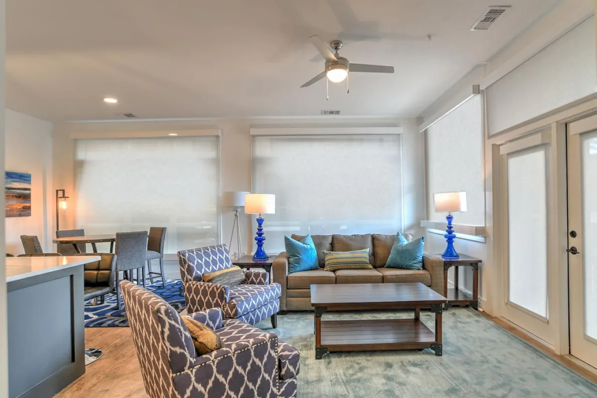 This interior scene showcases a cozy living area with a sofa, accent chairs, and a coffee table. The space is bathed in natural light, suggesting proximity to a balcony or large windows, with furnishings arranged for relaxing or socializing—activities that echo balcony use.
